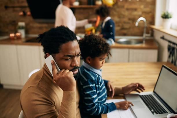 istock Black stay at home father talking on the phone while working at home. 1287923651