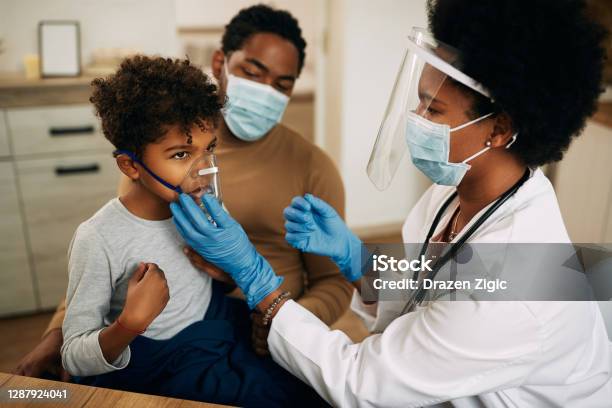 Small Black Boy Receiving Asthma Treatment While Doctor Is Vising Him At Home Due To Covid19 Pandemic Stock Photo - Download Image Now