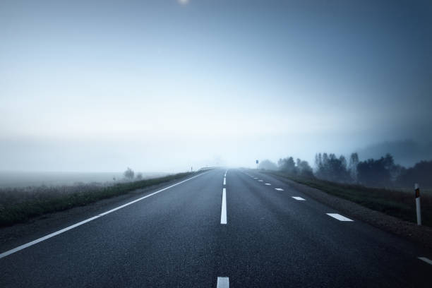 Panoramic view of the empty highway through the fields in a fog at night. Moonlight, clear sky. Sunrise. Europe. Transportation, logistics, travel, road trip, freedom, driving. Rural scene Panoramic view of the empty highway through the fields in a fog at night. Moonlight, clear sky. Sunrise. Europe. Transportation, logistics, travel, road trip, freedom, driving. Rural scene night freeway stock pictures, royalty-free photos & images