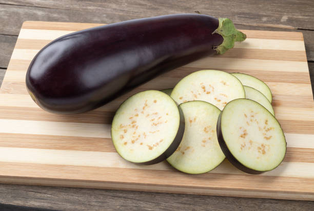 istock Raw eggplant with slices over wooden board 1287930648