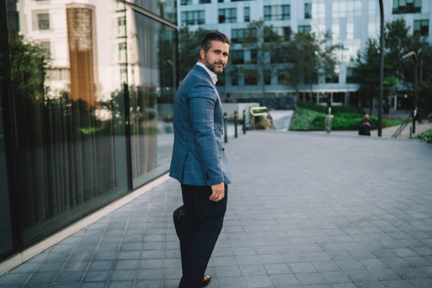 successful businessman dressed in trendy jacket looking at camera while walking in downtown, full length portrait of mature male entrepreneur 40 years old in formal wear posing at urban street - 35 40 years fotos imagens e fotografias de stock