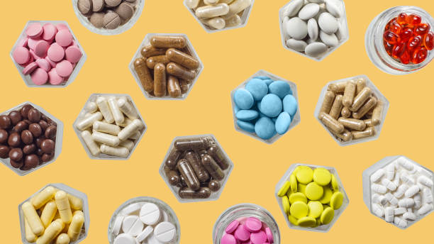 istock Medical capsules and pills in hexagonal jars on yellow background 1287936861