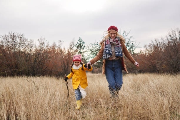 istock Happy mother and daughter holding hands while running through forest meadow on a winter day 1287937036
