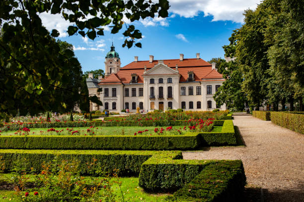 The side of a country house and garden with flowers and ornate wall.