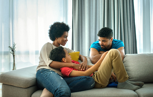 Closeup side view of an african american and hispanic family staying at home during coronavirus quarantine. They are relaxing on a sofa and talking.