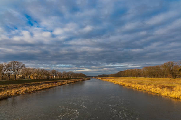 istock Cloudy landscape of river between yellow coasts and trees 1287941950