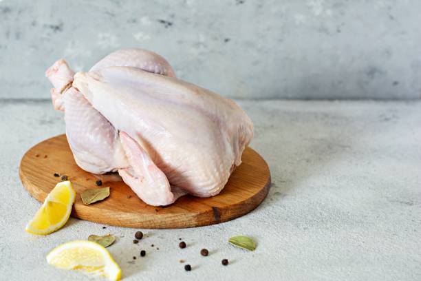istock Raw chicken carcass ready for cooking on a cutting board on a gray background. 1287944999