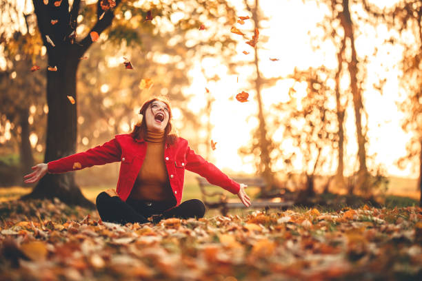 istock Woman throwing fallen autumn leaves 1287946046
