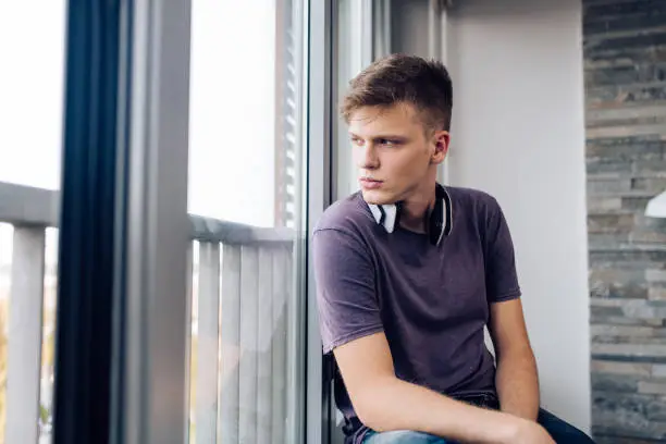 Photo of Portrait of a boy looking through the window thoughtfully