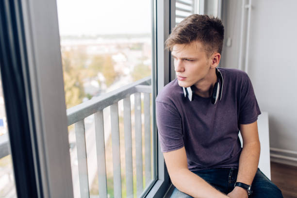 istock Portrait of a thoughtful boy looking through the window 1287949296