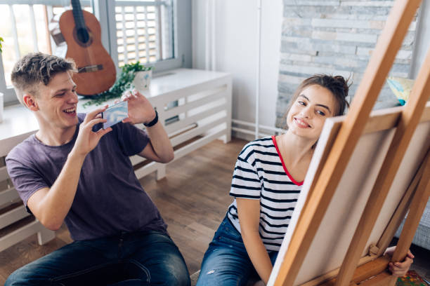 istock Young man taking a photo of his girlfriend's artwork 1287950013