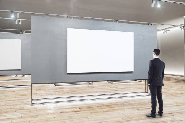 istock Businessman looking on blank banner in exhibition room. 1287952940