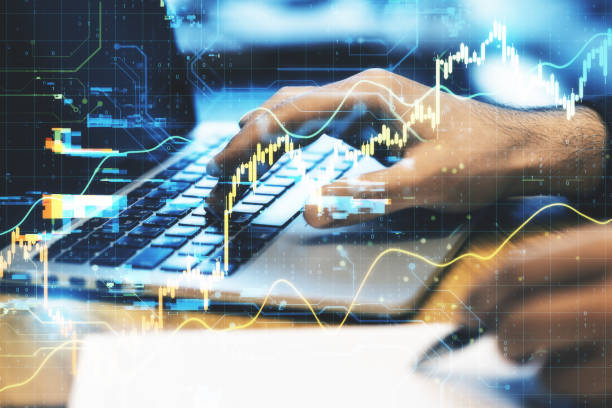 istock Hand typing on laptop computer on desktop with stock charts 1287953561