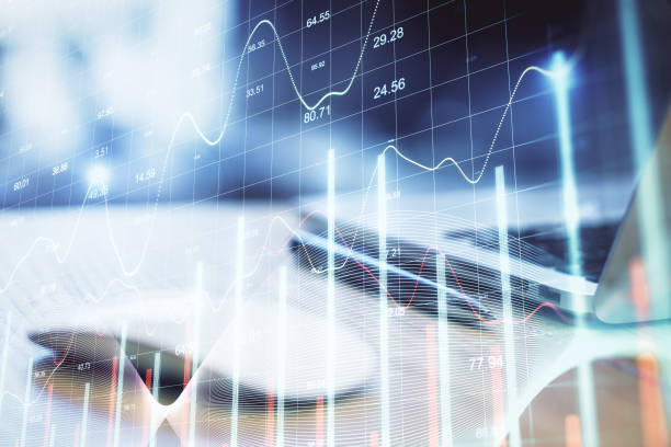 istock Computer mouse and laptop on table with stock charts 1287953739