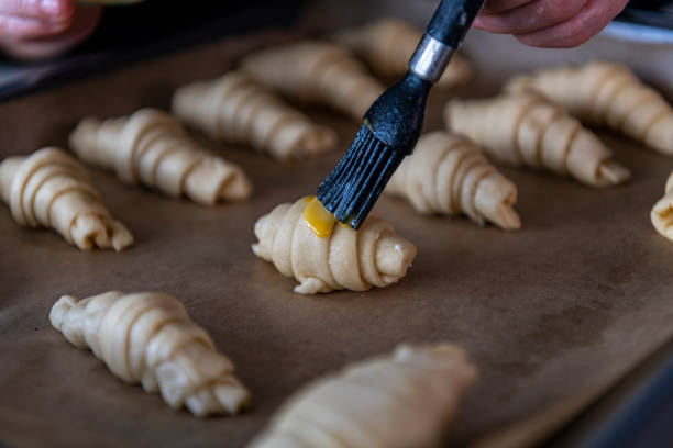 istock Baker putting yolk on croissants 1287958094