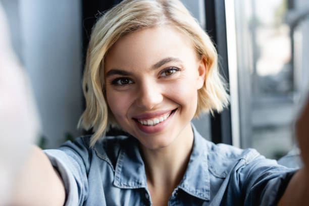 istock blonde woman smiling and looking at camera with blurred foreground 1287961057