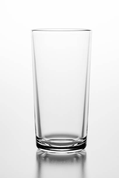 istock Empty glass on a white table. Glass container for storing water. Light background. 1287964496