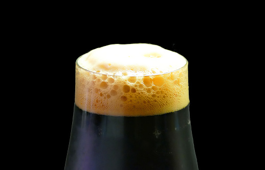 Foam of stout beer cut under a black background.