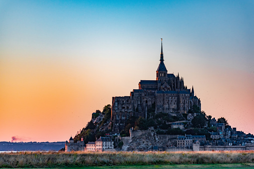 Le Mont-Saint-Michel – Saint Michael's Mount is a tidal island and mainland commune in Normandy, France. Mont Saint-Michel and its bay are on the UNESCO list of World Heritage Sites. It is visited by more than 3 million people each year. Over 60 buildings within the commune are protected in France as monuments historiques. \n\nThe presence of the community attracts many visitors and pilgrims who come to join in the various liturgical celebrations.\n\nDue to its status as a popular place for pilgrimage, is completely freely accessible without any entrance fees or restrictions.