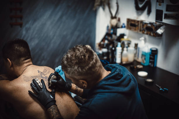 istock One male tattoo artist tattooing a man's back 1287968281