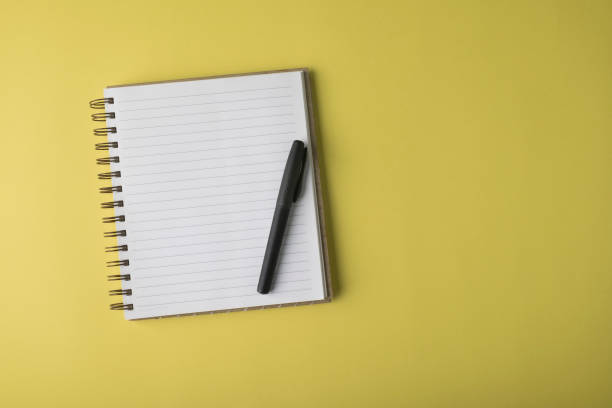 istock Blank Notebook And Black Pen On Yellow Background 1287968296
