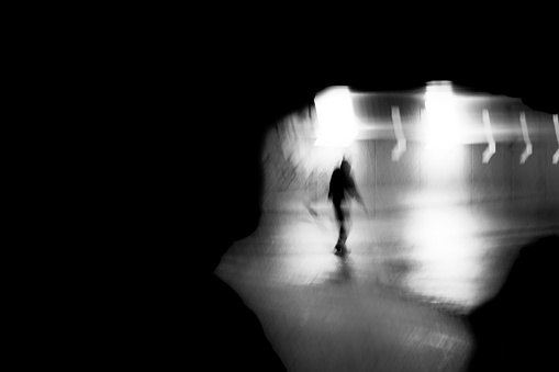 young person in silhouette moving through a tunnel at night