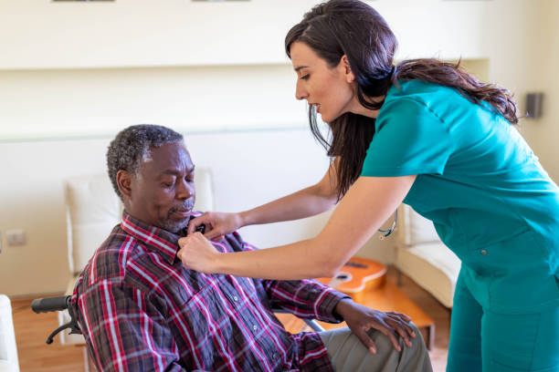 Home caregiver dressing senior man