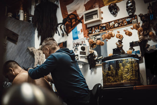 Tattoo artist tattooing a man's back in his tattoo studio.