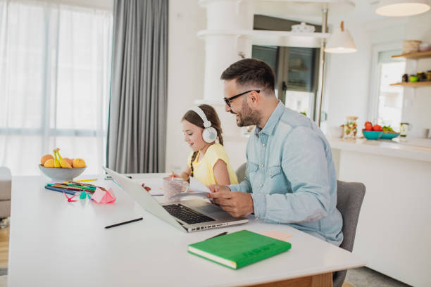 istock Father is working from home and his daughter is writing homework 1287977197