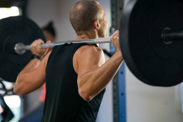 istock Man doing squats with barbell weights in home gym 1287983363