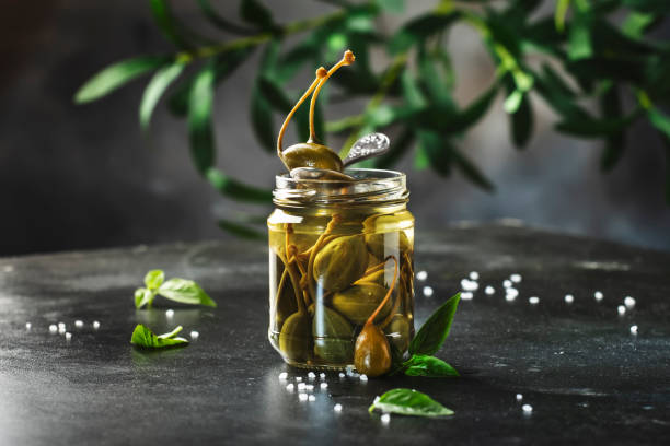 istock Marinated or pickled canned capers fruit close up in jar on gray kitchen table with copy space 1287984571