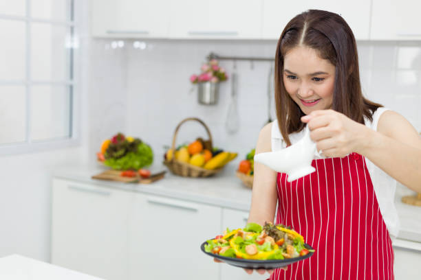 istock Young Asian woman making salad in kitchen. 1287992501
