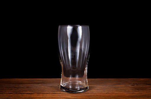 Beer glass on a wooden table isolated on a black background.