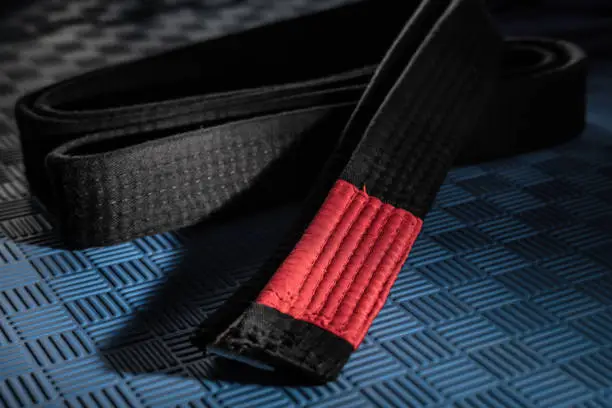 Close up on brazilian jiu jitsu bjj black belt on the tatami mats - martial arts grappling and training concept dark and high contrast filter