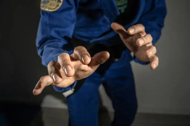 Close up on hands of unknown brazilian jiu jitsu bjj or judo grappler in fighting stance - front view midsection martial arts training concept