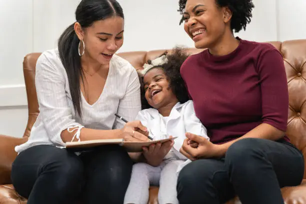 Photo of LGBT diversity Lesbian Couple Moments Happiness with her african girl laughing and drawing picture