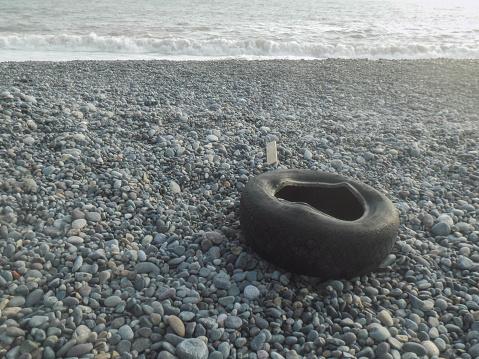 The shot shows a used tire thrown on pebble beach.
