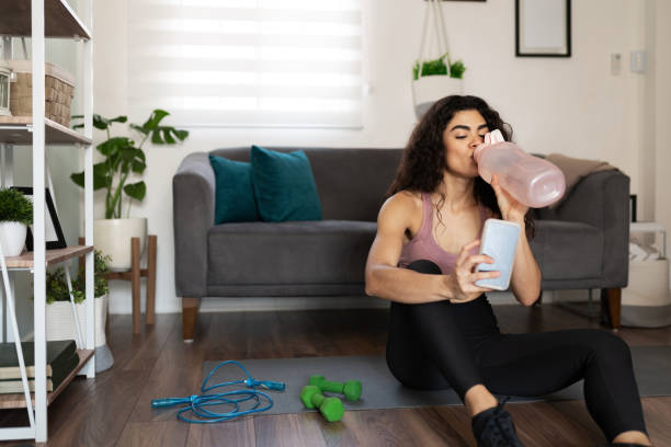 istock Athletic hispanic woman drinking from a water bottle and using her phone 1287999973