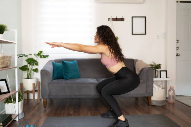 istock Hispanic woman practicing squat exercises at home 1288000745