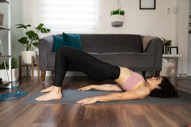 istock Active latin woman exercising and doing a bridge yoga pose at home 1288000968