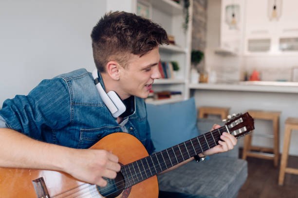istock Young musician playing a guitar at home 1288005806