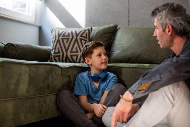 istock Son and his father sitting at the floor, talking. 1288012550