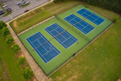 Drone shot of tennis courts in a local county park in the suburbs of Atlanta which is being used for recreation during pandemic while maintaining social distance.