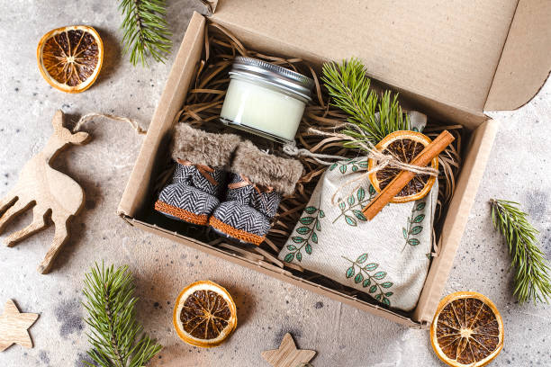 istock Holiday christmas gift box with cozy items textile pouch, candle, small boots. Care package concept 1288018405