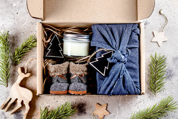 istock Holiday christmas gift box with cozy items textile pouch, candle, small boots. Care package concept 1288018412