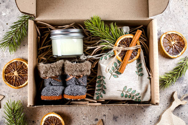 istock Holiday christmas gift box with cozy items textile pouch, candle, small boots. Care package concept 1288018431