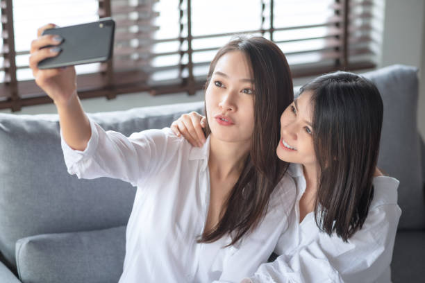 istock Two asian female using mobile phone and internet technology to use video call to other friends 1288024000