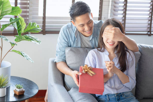 istock Handsome man is giving his girlfriend a red gift box for birthday surprising 1288024008