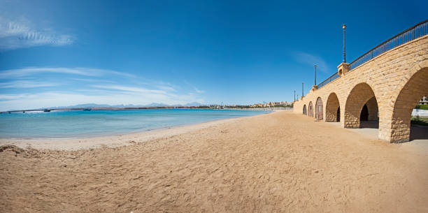 View across an empty tropical beach with stone bridge and arches
