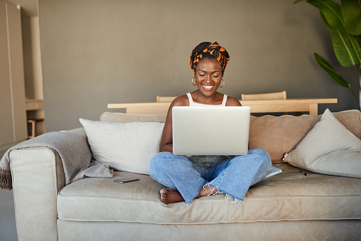 Shot of a young woman using a laptop on the sofa at home
